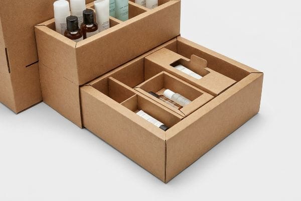 Modular brown kraft cardboard display featuring nested components and interchangeable dividers, organizing small cosmetic bottles and tubes.