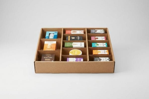 Brown corrugated cardboard display tray with modular dividers showcasing various small product boxes in an asymmetrical layout.
