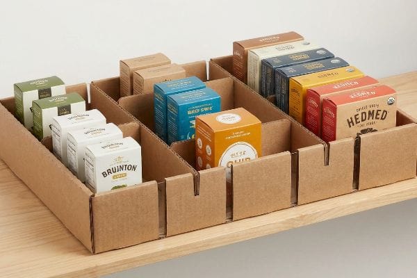 Corrugated cardboard display tray with modular dividers organizing various Bruinton, Brd Swie, Hedmed, and Pure Gold product boxes.