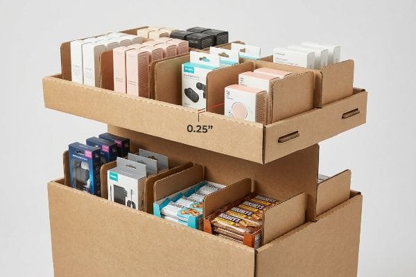 Corrugated cardboard display with modular dividers shows a 0.25-inch clearance, organizing electronics and snacks.