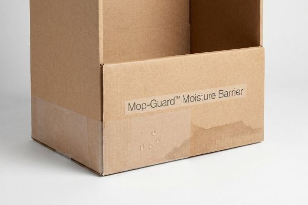 Transparent Mop-Guard™ Moisture Barrier on a brown corrugated box, effectively repelling water droplets and preventing wicking.
