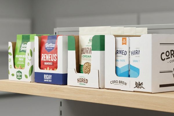 Retail shelf displays various branded PDQ trays, including Maltes Green, Bettar Reneus, Hurn Organic, and Coro Bren, showcasing products in organized cardboard packaging.