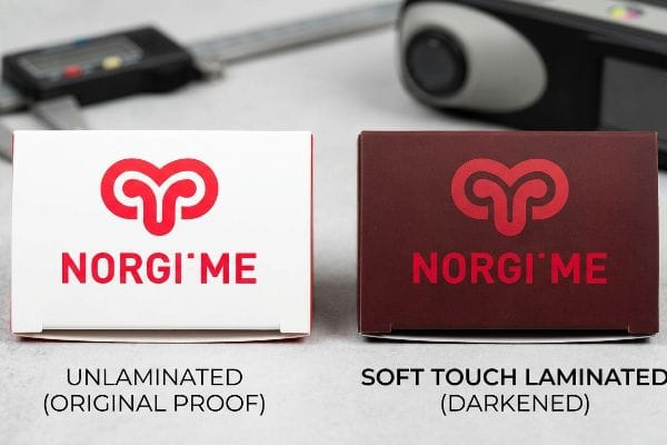 Comparaison des emballages Norgi'me : boîte d'épreuve originale non laminée à côté d'une version laminée Soft Touch et assombrie.