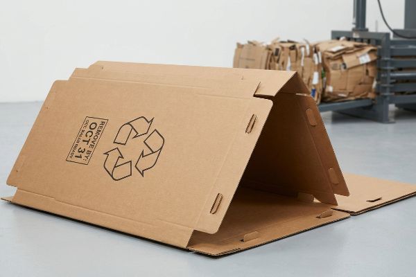 Brown corrugated cardboard display with a black recycling symbol and 'Remove By: Oct 31, Occ Baler Ready' text, designed for rapid teardown.