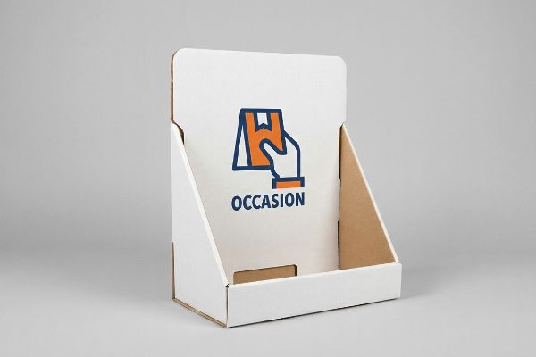 A white corrugated cardboard display features an orange and blue icon of a hand holding a package, with 