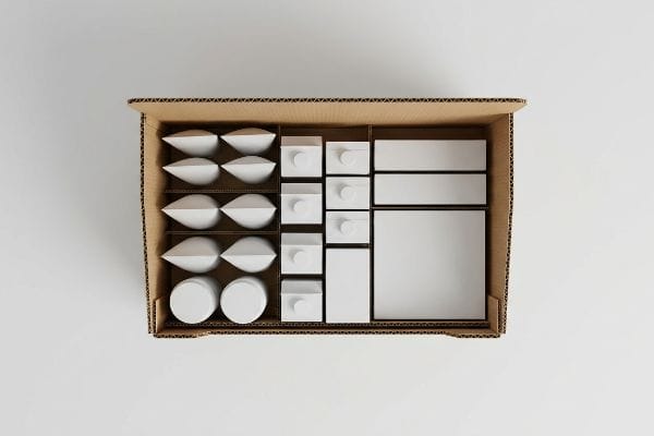 Retail Packaging Organization Organized corrugated box with white packaging components: teardrop inserts, small boxes, and larger rectangular containers for retail.