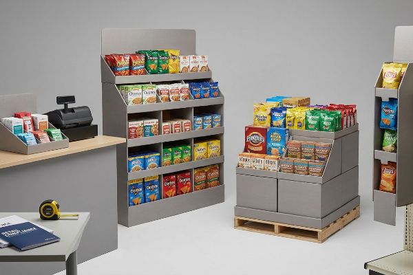 Grey POP displays: a pallet merchandiser, floor-standing unit, and countertop tray with a cash register, stocked with Cheetos, Doritos, and Lay's snacks.