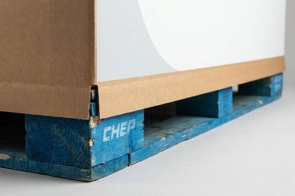 A corrugated cardboard pallet skirt with an interlocking design rests on a blue Chep wooden pallet, showing a clearance buffer.