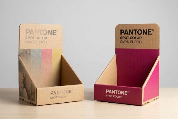 Le carton ondulé présente une impression CMJN granuleuse contrastant avec un magenta Pantone Spot Color Flood vibrant sur du papier testliner.