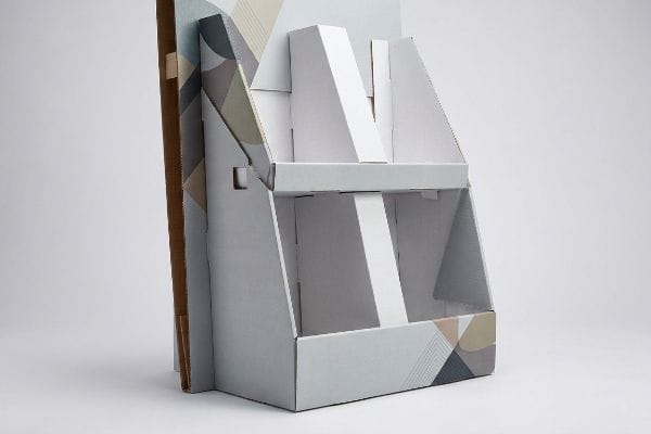 Partially assembled free standing cardboard display with a light grey finish and geometric pattern.