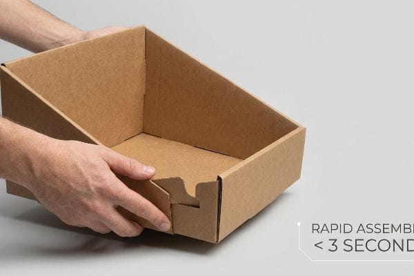 PDQ-Displaytablett aus brauner Wellpappe mit ineinandergreifenden Laschen, von Hand zusammengebaut, mit dem Hinweis „Schnelle Montage < 3 Sekunden“.