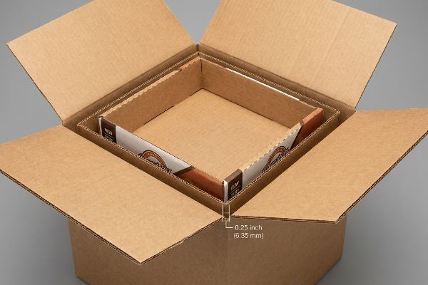 Brown corrugated shipping box with an inner display tray showing a 0.25 inch (6.35 mm) perimeter clearance.