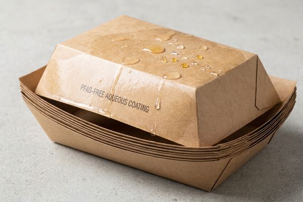 Brown Kraft paperboard food trays featuring Pfas-Free Aqueous Coating, demonstrating water resistance.