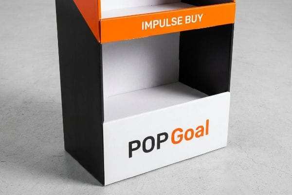 A multi-tiered black, white, and orange POP display featuring 'Impulse Buy' and 'POP Goal' text.