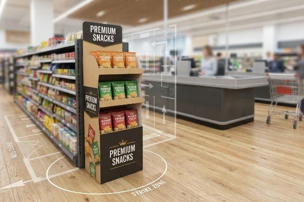 A retail store aisle features a cardboard point-of-purchase display for Premium Snacks, positioned within a marked traffic flow and strike zone.