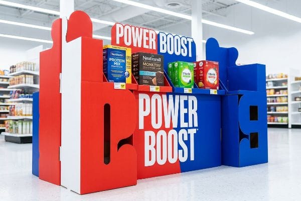 Red and blue corrugated Power Boost retail display, featuring Nutriboost Protein Mix, Neatntrall Monktry, and D'Booster products.