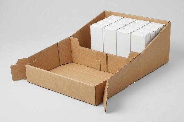 Brown corrugated cardboard PDQ display with white product boxes, showcasing pre-glued retail-ready assembly.
