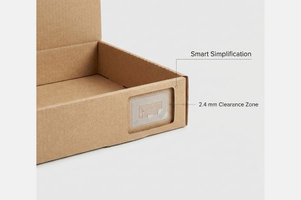 Brown corrugated cardboard box with an embedded RFID tag, highlighting the Smart Simplification and 2.4 mm Clearance Zone for tracking hardware protection.
