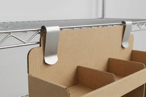 Brushed stainless steel S-clips securely hang a corrugated cardboard display with internal dividers from a metal wire shelf.
