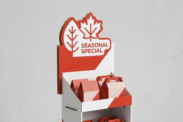 Seasonal Display Gable Boxes Cardboard seasonal display with a red die-cut header featuring a maple leaf and leaf icon, displaying "Seasonal Special" text. It holds red and white gable boxes.