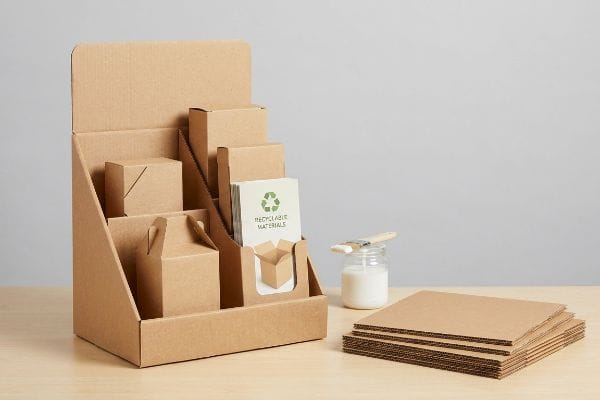 Corrugated cardboard POP display with small boxes, a 'Recyclable Materials' card, PVA adhesive, and flat single-wall sheets.