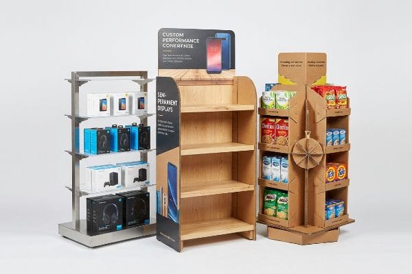 Drei Verkaufsdisplays: ein permanentes Metalldisplay, ein semi-permanentes Display in Holzoptik und ein temporäres Drehdisplay aus Wellpappe mit Snacks.