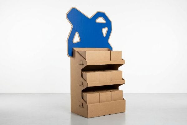 Brown corrugated cardboard endcap display with three shelves holding nine plain boxes, topped by a striking blue die-cut header.