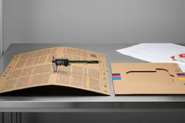 Corrugated Board Bowing Measurement A digital caliper measures 3.5mm bowing on a CMYK-printed corrugated board, illustrating warp from heavy ink saturation.