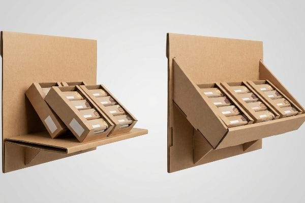 Brown corrugated cardboard display with two angled shelf configurations holding individually wrapped bars, demonstrating gravity-defying design.