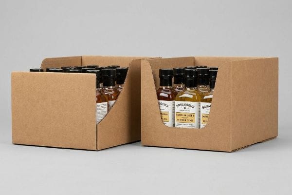 Brown cardboard display trays feature custom die-cut swoops, revealing Broadmoen's Barbados Origin glass bottles, optimizing impulse sales.