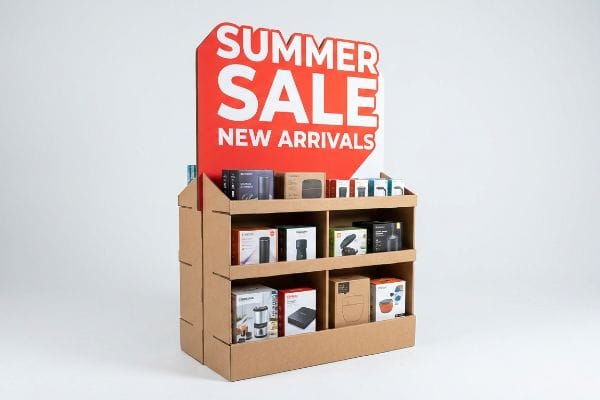 Cardboard retail display with a red 'Summer Sale New Arrivals' header, showcasing various boxed products on three shelves.
