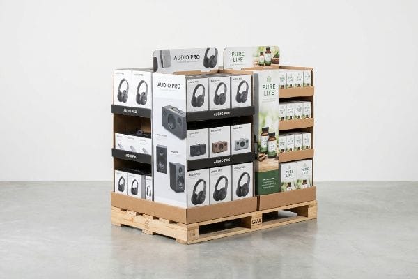 Cardboard pallet display showcasing Audio Pro headphones and speakers alongside Pure Life health products on a wooden GMA pallet.