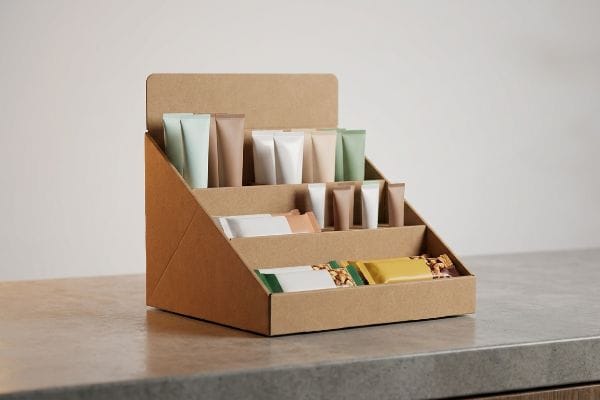 PDQ Tray Display Products A countertop cardboard PDQ tray display features pastel cosmetics tubes and individually wrapped snack bars, ideal for impulse buys.