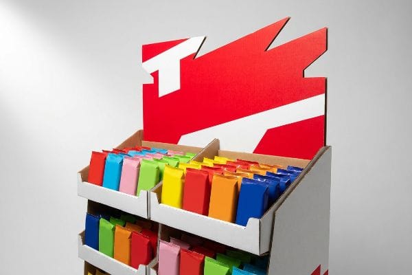 नालीदार कार्डबोर्ड से बना FMCG डिस्प्ले, जिसमें लाल और सफेद रंग के डाई-कट हेडर का इस्तेमाल किया गया है, जो जीवंत रंगीन उत्पाद पैकेजों को प्रदर्शित करता है।.