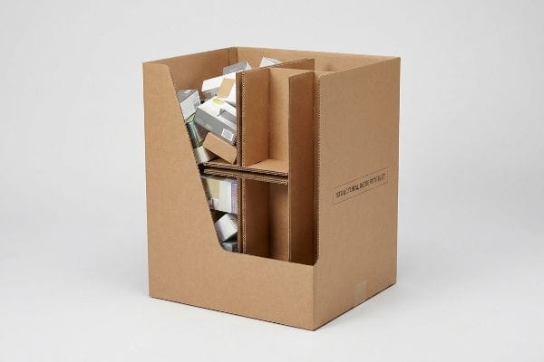 Dump Bin H-Divider Test Brown corrugated dump bin with an internal H-divider, partially filled with small retail boxes, labeled "Structural Integrity Test".
