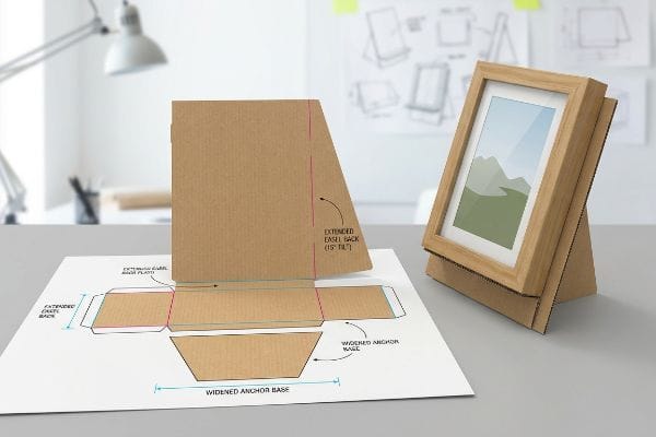 Brown corrugated cardboard dieline for an Extended Easel Back (15° Tilt) and an assembled stand supporting a picture frame, illustrating the Widened Anchor Base.
