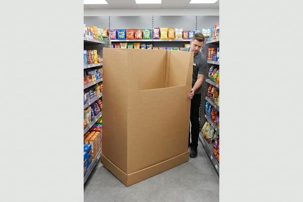 Retail Floor Display Logistics Brown corrugated cardboard floor display being moved by a store employee in a narrow retail aisle, illustrating CPG physical packaging logistics.