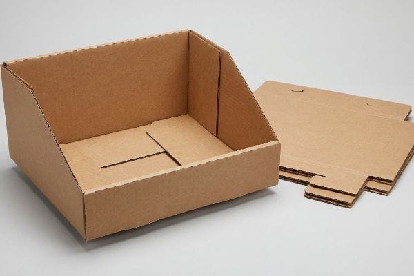 Natural kraft corrugated cardboard PDQ display tray, partially assembled with auto-locking bottom, next to flat unassembled retail-ready pieces.