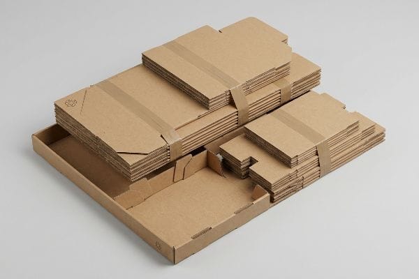 Unassembled corrugated cardboard display components, flat-packed for efficient shipping, featuring a visible recycling symbol on some pieces.