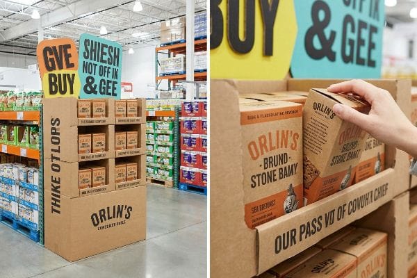 Orlin's Merchandising Display Brown cardboard Orlin's display in warehouse, with 'Give Buy' and 'Shiesh' signs, a hand selecting Brund-Stone Bamy product.