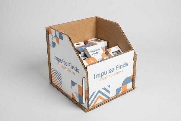 Corrugated cardboard dump bin featuring 'Impulse Finds Retail Solutions' branding and orange-blue geometric patterns, filled with small product boxes.