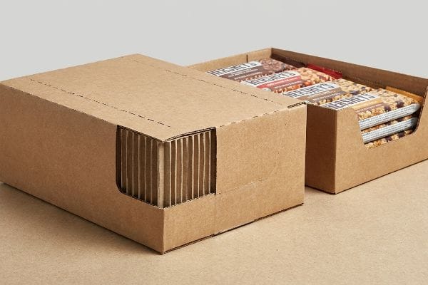 Two brown corrugated PDQ display boxes, one open with Hershey's snack bars, ready for retail merchandising.