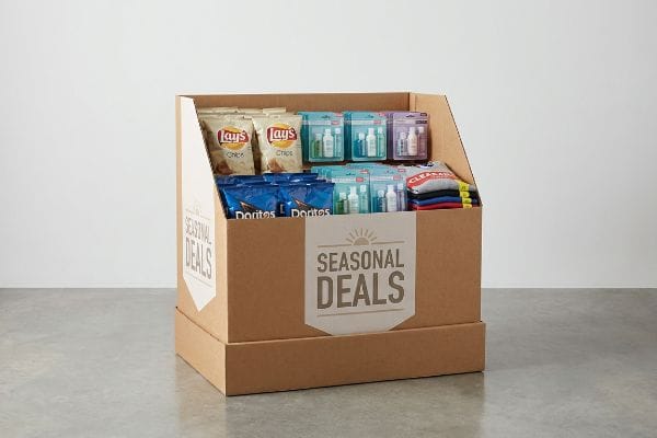 A cardboard dump bin display features "Seasonal Deals" with Lay's chips, Doritos, travel-sized cosmetics, and "Clearance" apparel, ideal for impulse buys.