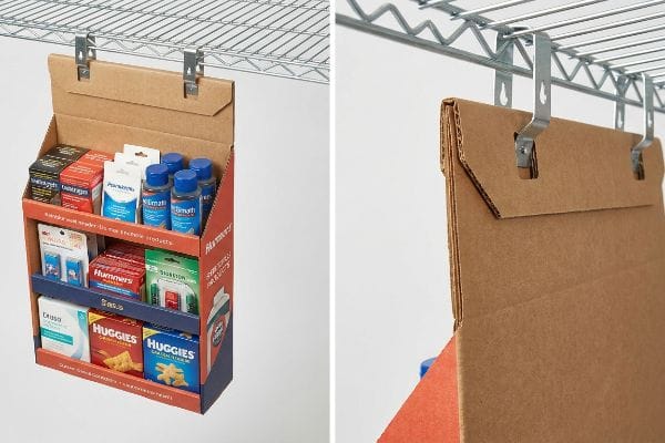 Sidekick Display Hanging Mechanism Corrugated cardboard point-of-purchase sidekick display, featuring a double-wall anchor and metal S-clips, hangs from a wire shelf, merchandising Huggies, Elimyth, and various impulse items.