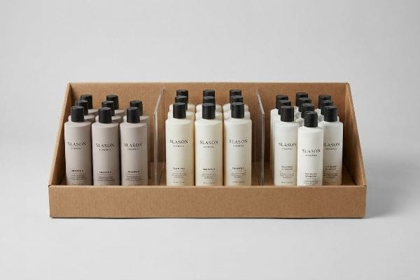 Brown corrugated cardboard display tray showcasing Slason Shampoo CPG items in modular dividers, with light brown, off-white, and white bottles.