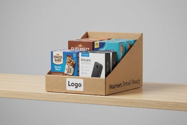 A Walmart Retail-Ready corrugated PDQ display tray on a wooden shelf, featuring Snack Bars, Electric devices, and Elite Direct products.