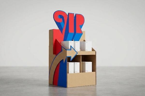 Corrugated cardboard point of purchase display featuring a prominent red and blue 3D 'ZIP' logo, directional arrows, and white product boxes.