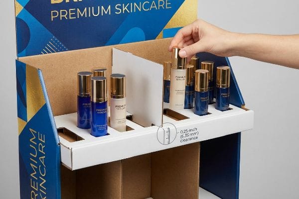 Skincare Display Clearance Restocking Cardboard Premium Skincare display with a hand placing a bottle, highlighting the 0.25-inch (6.35 mm) clearance for frictionless restocking.