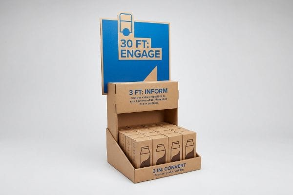 3-3-3 Rule Display Brown corrugated retail display demonstrating the 3-3-3 rule with a blue "30 Ft: Engage" header, "3 Ft: Inform" section, and "3 In: Convert" product visibility.