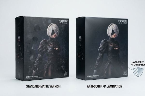 Anti-Scuff Lamination Comparison Two premium action figure boxes comparing Standard Matte Varnish with visible scratches to pristine Anti-Scuff PP Lamination.